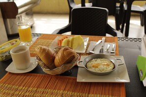 Una tavola imbandita per la colazione con pane, uova e succo di frutta.