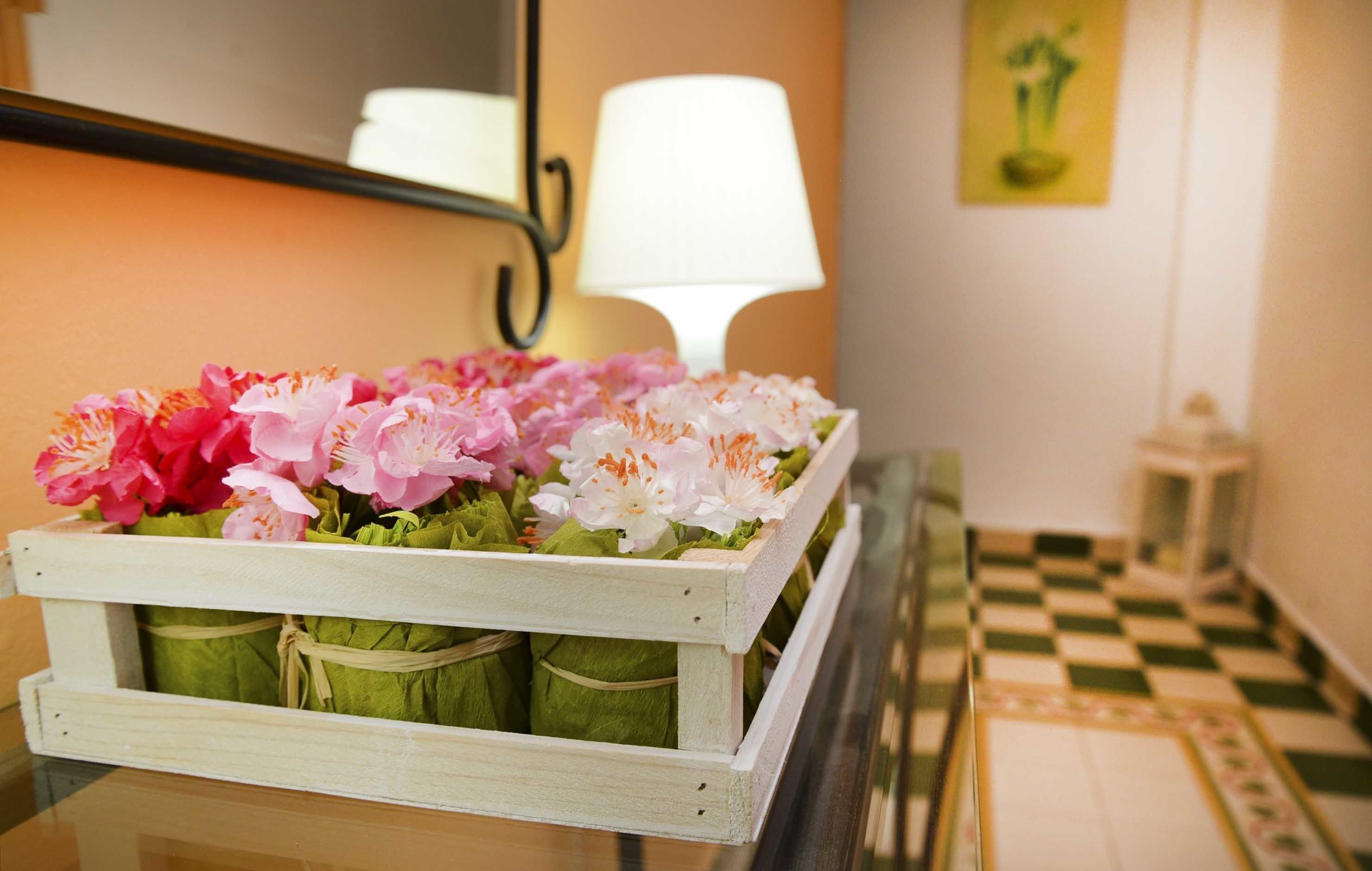 A wooden crate with flowers and a lamp in the background.