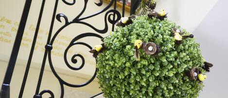 A hanging green plant with bird figurines and a decorative metal railing.