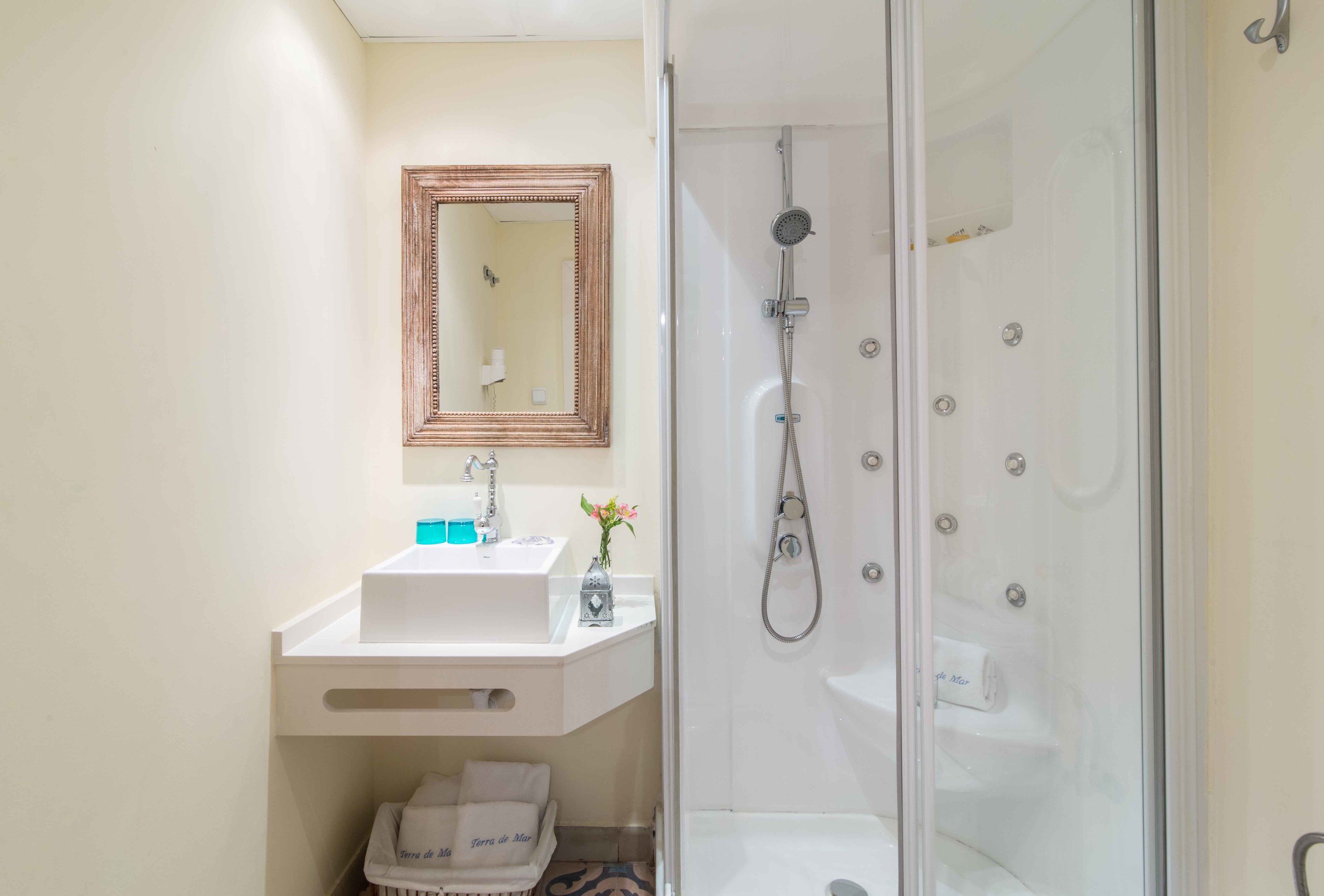 A bathroom with a white sink, mirror, and shower.
