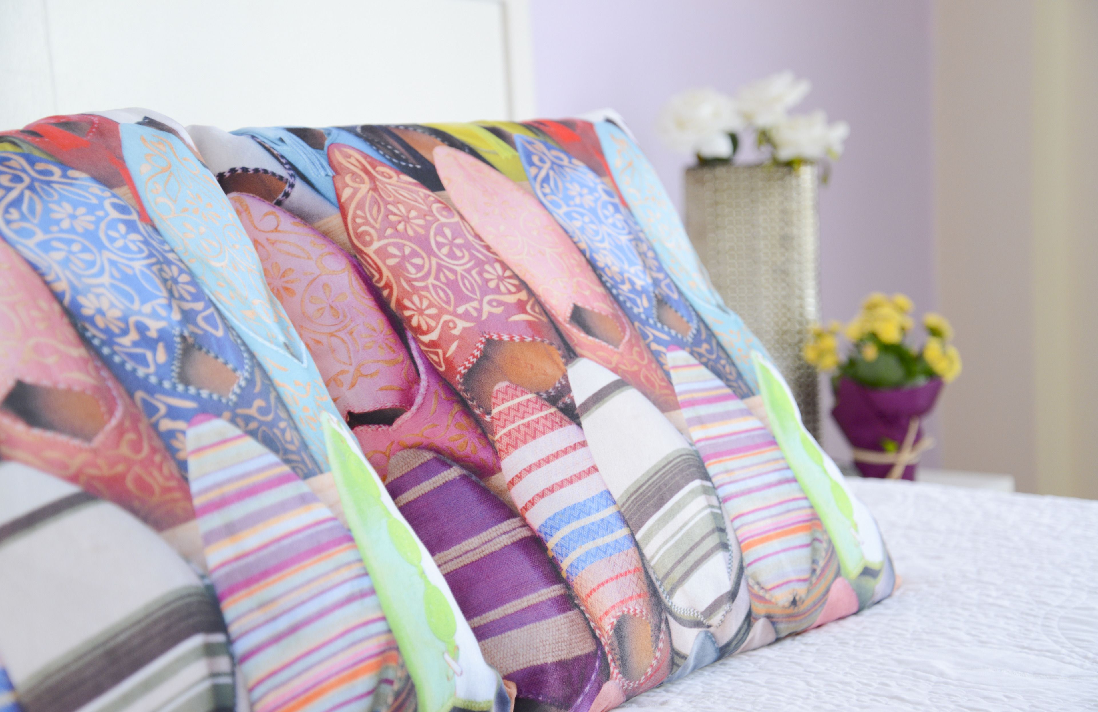 A bed with a white sheet and multiple colorful pillows with various patterns.