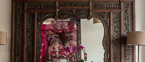 A mirror with intricate woodwork and a potted plant in front.