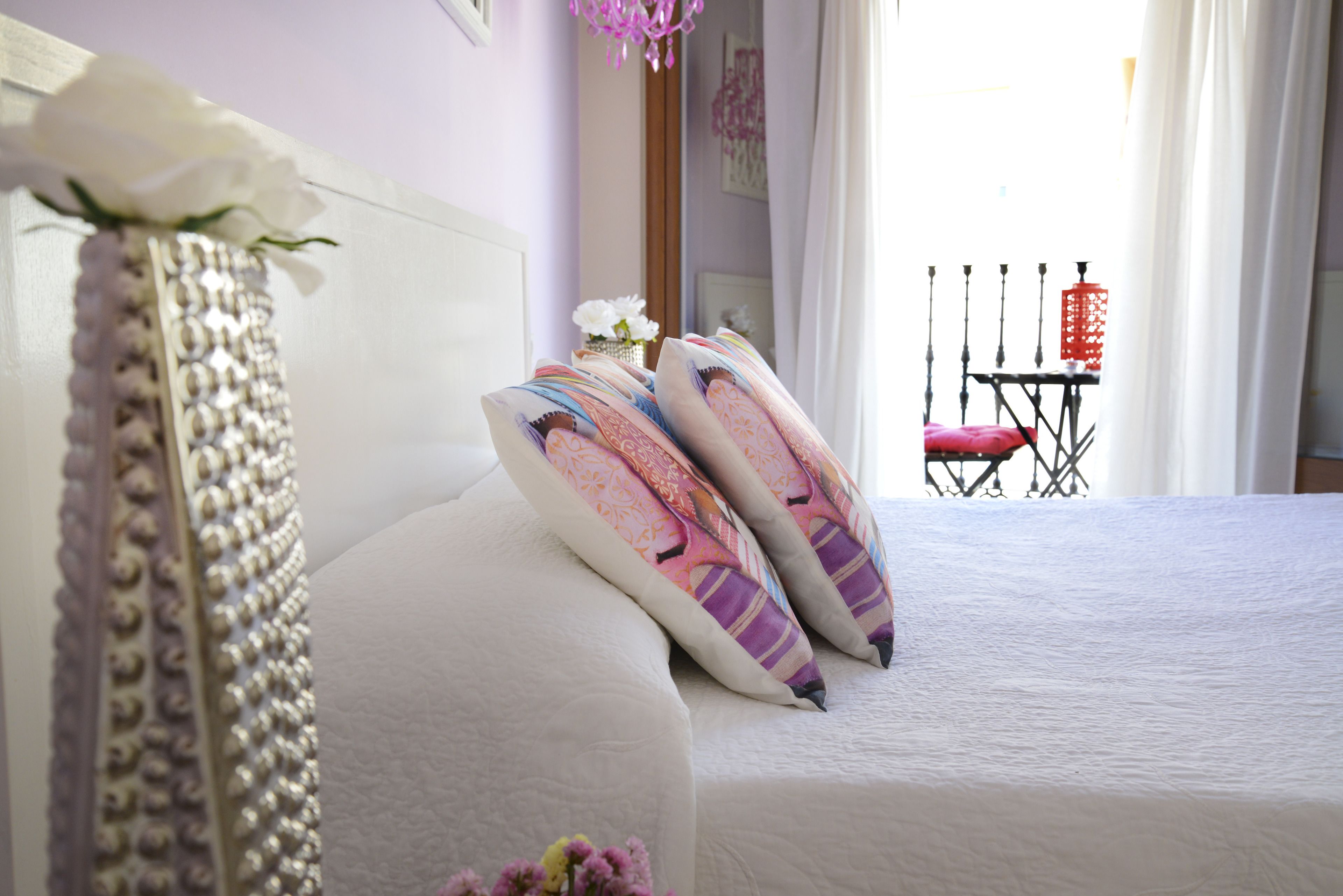 A neatly made bed with decorative pillows and a vase with flowers.