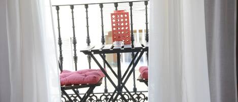 A balcony with a metal railing, a small table, and two pink cushions.