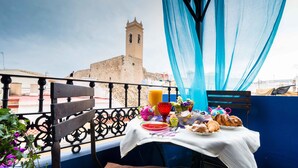 A balcony with a table set for breakfast, a view of a historic tower, and blue curtains. - Terra de Mar Boutique Calpe (Calpe)