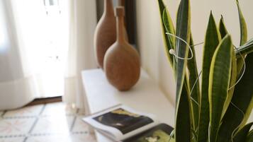 A room with a tiled floor, a white table with two vases, and a potted plant.