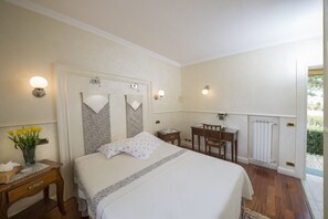 Une chambre à coucher avec un lit, une table de chevet, une lampe et une vue sur l’extérieur.