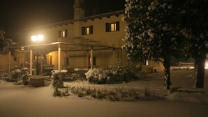 A snow-covered building with a covered outdoor area and a snow-covered tree. - Hotel La Rescossa (Mira)