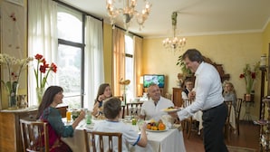 A dining room with a table set for a meal, surrounded by chairs, and a chandelier above. - Hotel La Rescossa (Mira)