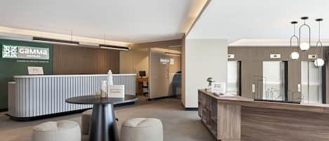 A hotel reception area with a modern design, including a reception desk, seating area, and a sign indicating the hotel name and location.