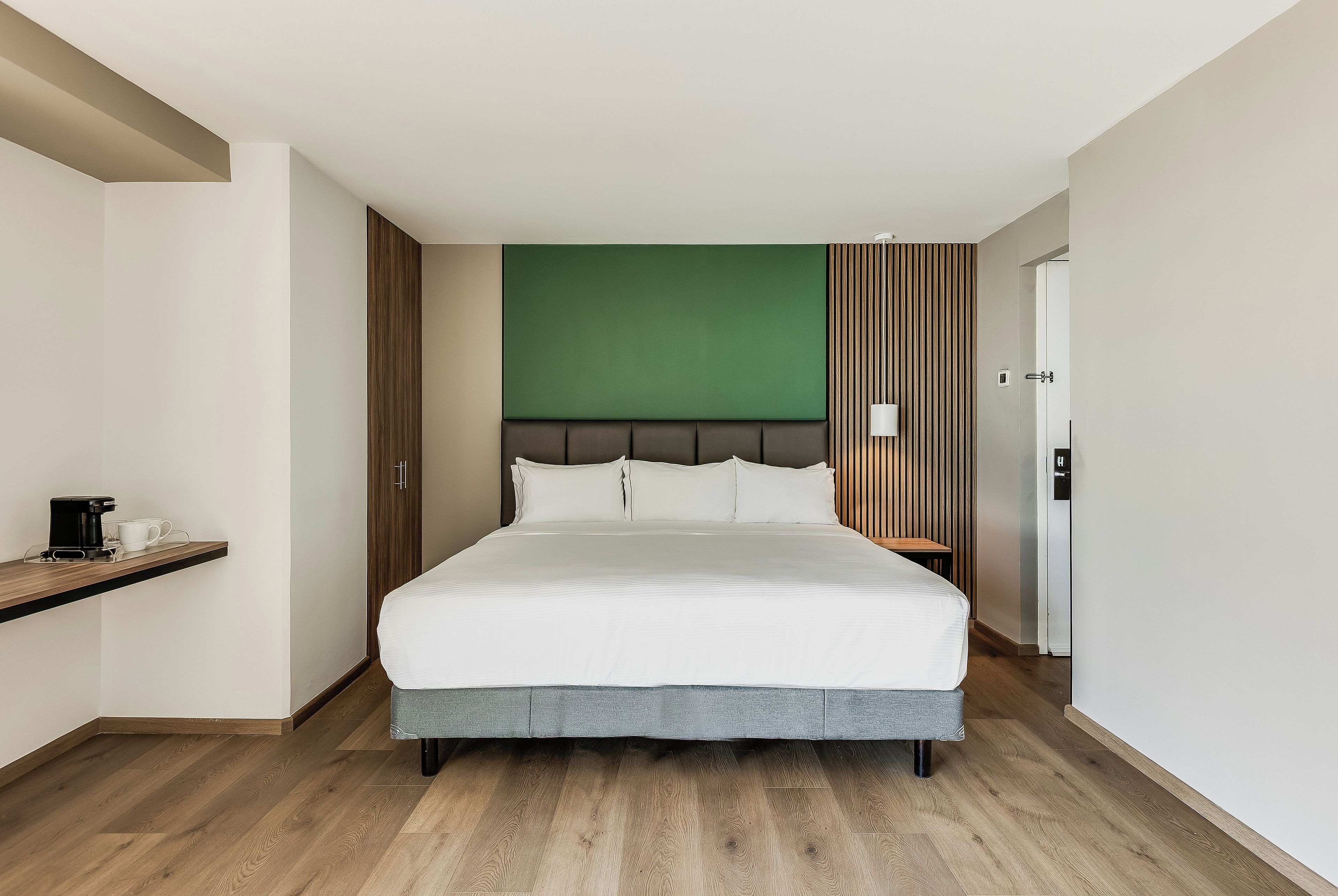 Una habitación de hotel con una cama, una cafetera y una mesita de noche.