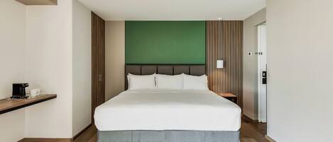 Una habitación de hotel con una cama, una cafetera y una mesita de noche.