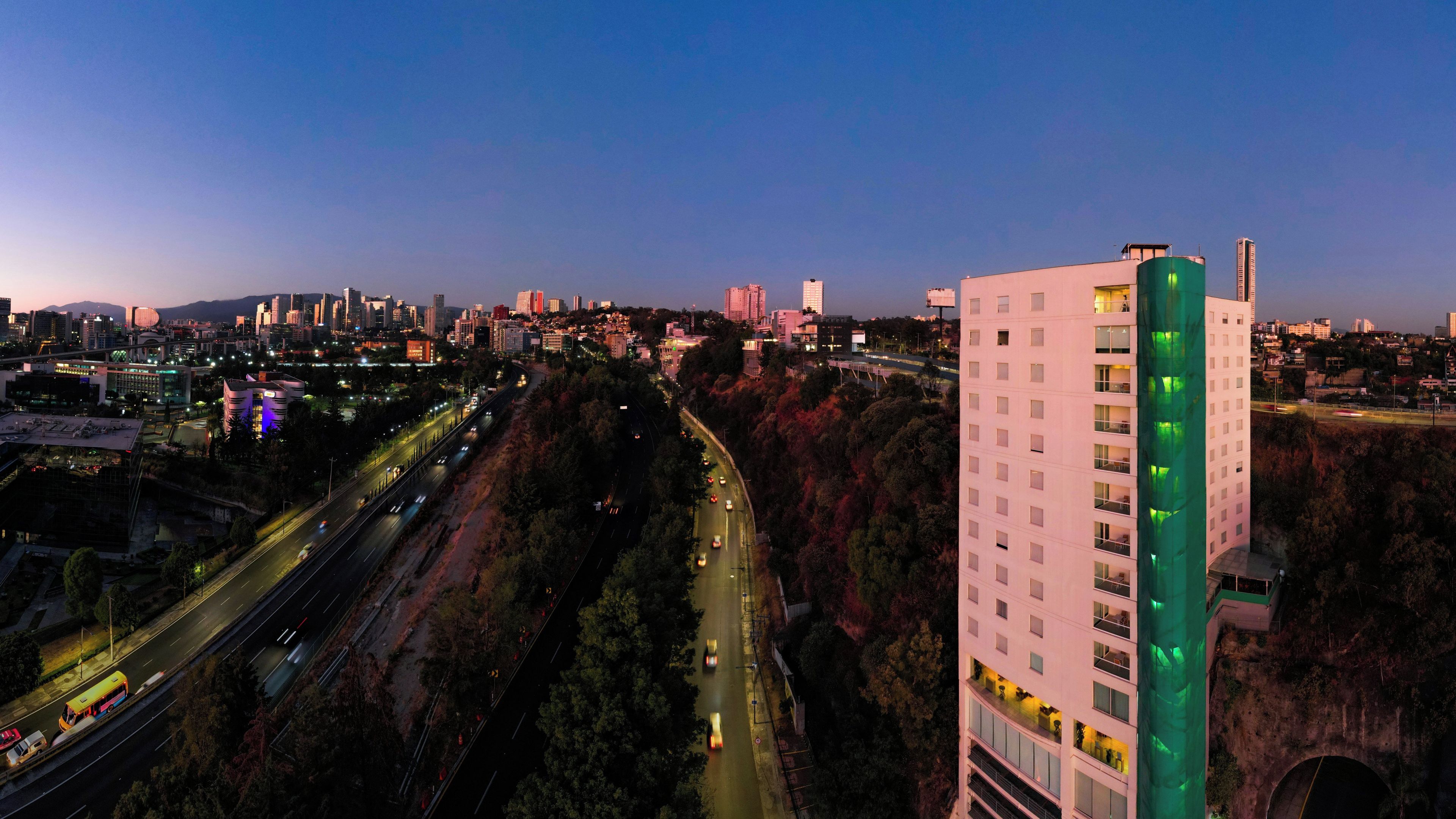 Un edificio de gran altura con varios pisos, una autopista y un paisaje urbano al fondo.