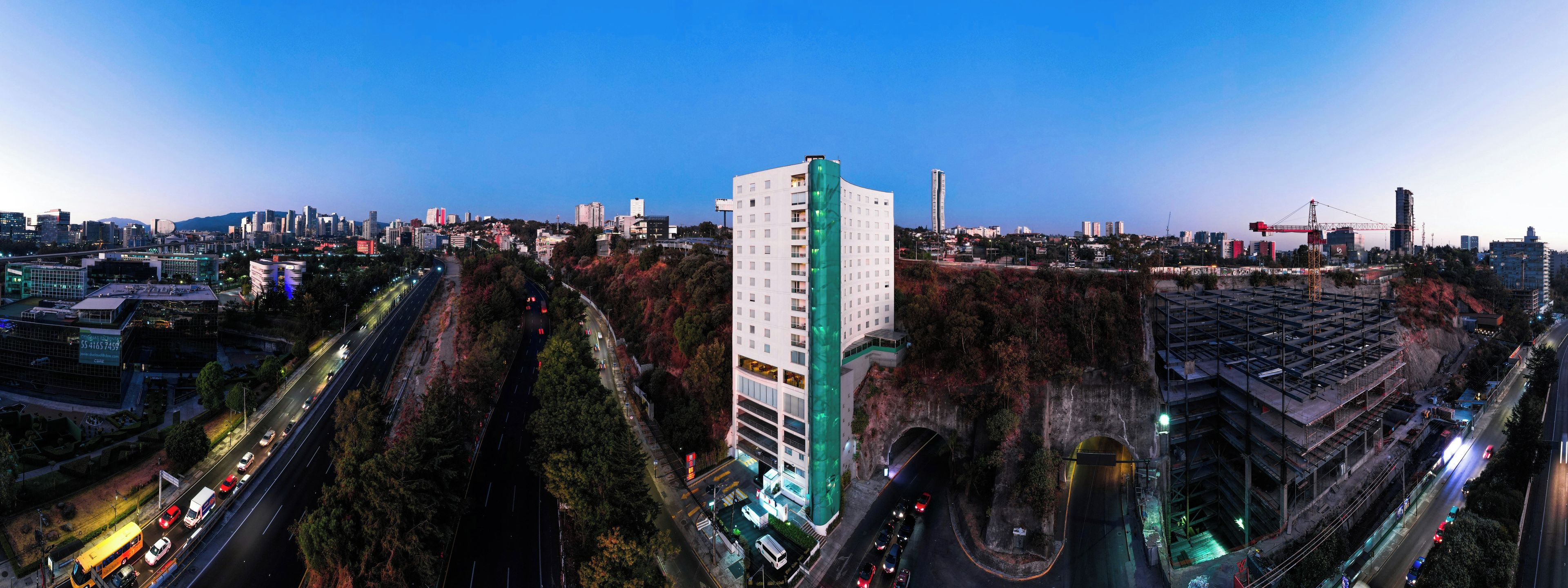 A cityscape with a prominent white building with a green accent, surrounded by roads and other buildings.