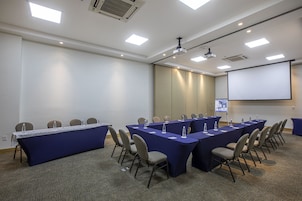 Une salle de conférence équipée d’une longue table, de nombreuses chaises et d’un écran de projection.