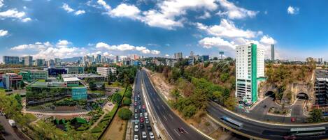 Un paysage urbain comprenant une autoroute, des immeubles et un espace vert traversé par une route.