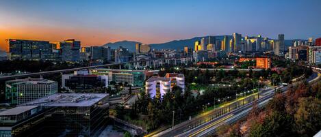 Un paisaje urbano con edificios modernos, una autopista y una montaña al fondo.