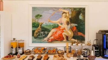 A breakfast buffet with pastries, bread, and spreads, and a classical painting above it.