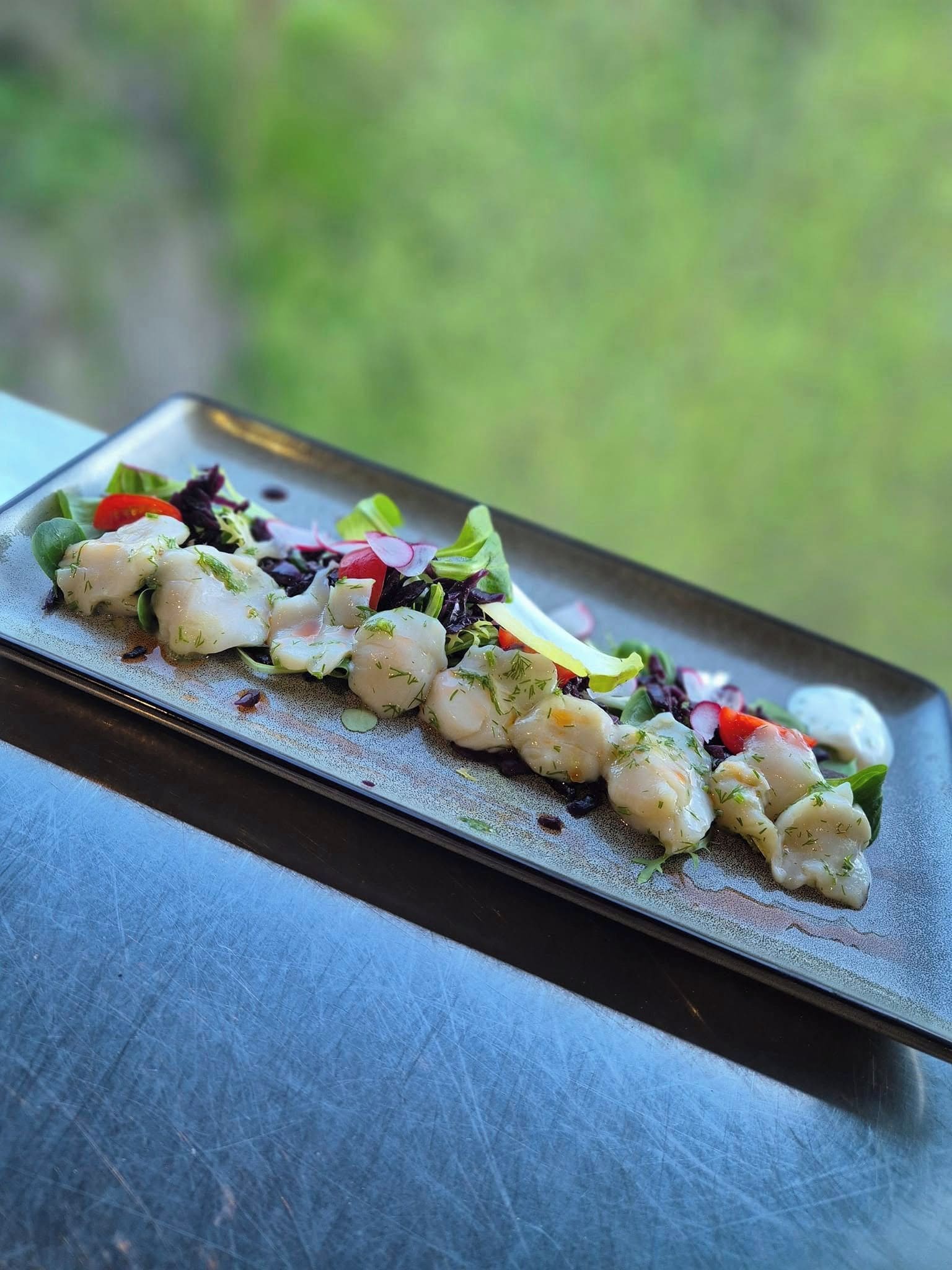 Un plato rectangular con una presentación de comida sobre una superficie texturizada.