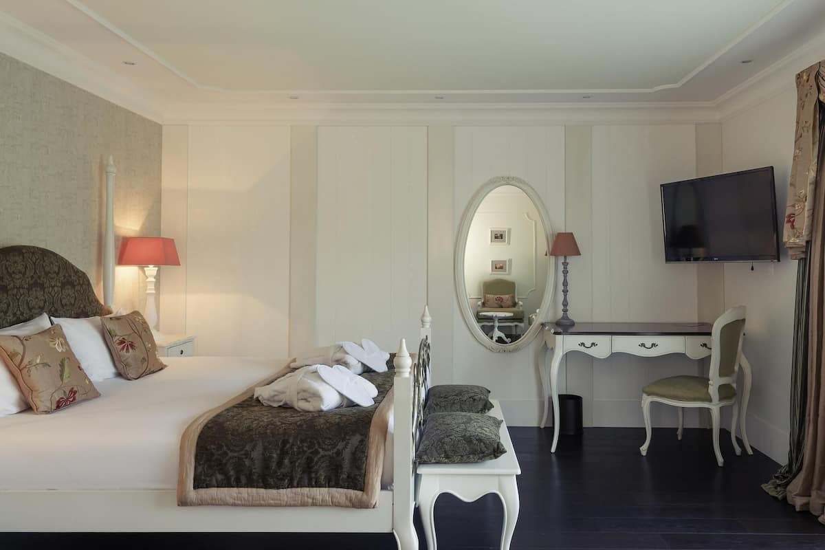 Ein Hotelzimmer mit Bett, Schreibtisch, Stuhl, Fernseher und Spiegel.