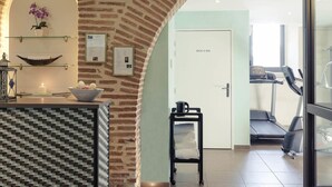 A room with a brick wall, a door labeled 'DOUCHE,' a treadmill, and a small table with a bowl.
