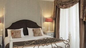 A bedroom with a bed, two bedside tables, a nightstand, a window with curtains, and a wall with a patterned wallpaper. - Hôtel Mercure Villeneuve sur Lot Moulin de Madame (Villeneuve-sur-Lot)