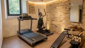 Une salle de sport à domicile équipée d’un tapis de course, d’un vélo elliptique et d’un rameur.