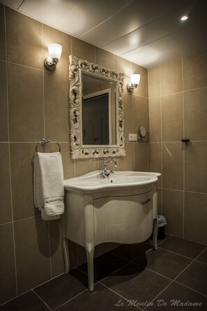 Classic bathroom with a pedestal sink, ornate mirror, and wall-mounted sconces.