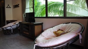 A room with a bed, a television, and a window with a view of palm trees.