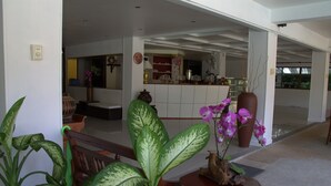 A spacious living area with a large plant, a wooden bench, and a vase with flowers.