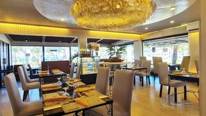 Un restaurante con mesas dispuestas para comer, un techo decorativo y amplias ventanas con vistas al exterior.