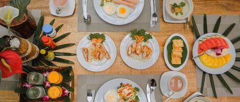 A table set with various dishes including fried eggs, rice, and vegetables, along with drinks and utensils.