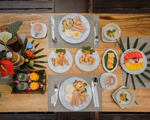 A table set with various dishes including fried eggs, rice, and vegetables, along with drinks and utensils. - The Vatika Resort and Spa (Krabi)