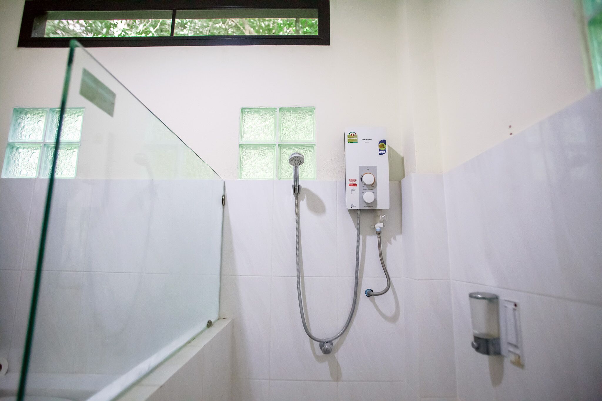 A bathroom with a glass shower enclosure, a wall-mounted showerhead, and a control panel.
