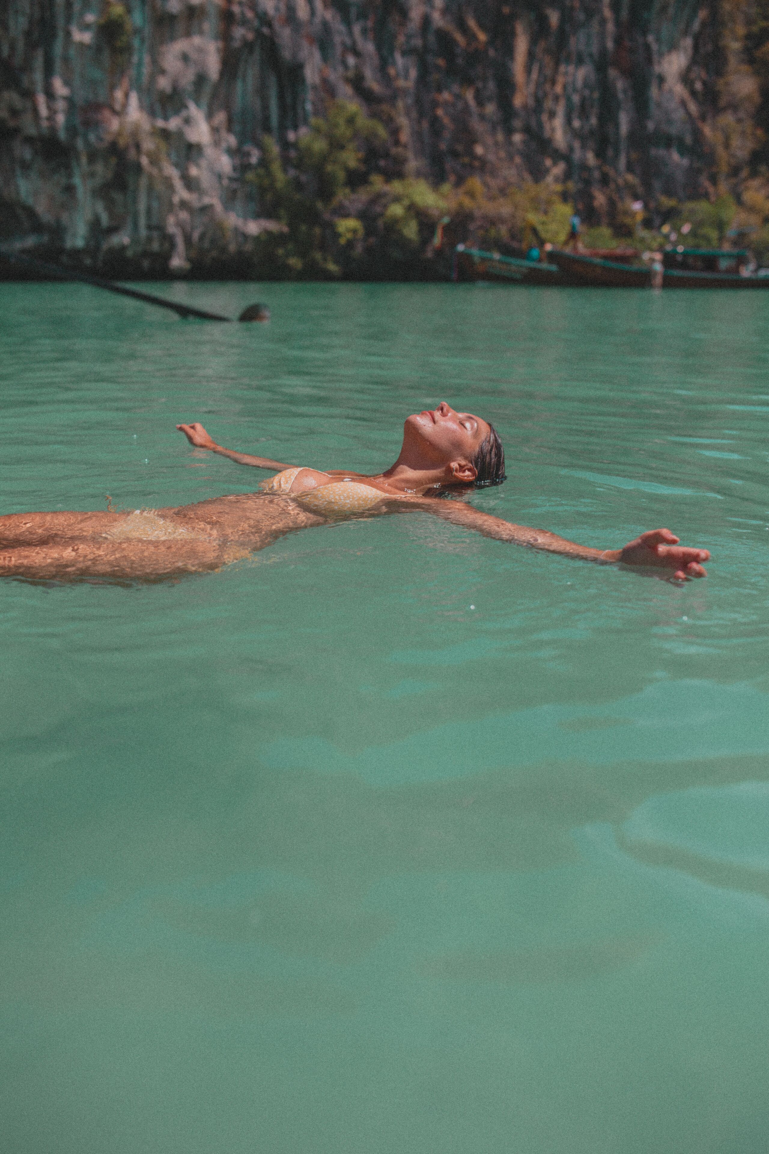 Eine Person treibt in klarem Wasser, im Hintergrund eine felsige Klippe.