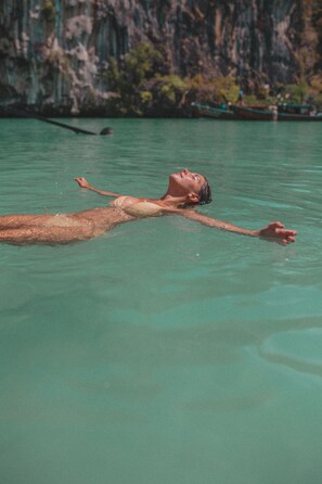 A person floating in clear water with a rocky cliff in the background. - The Vatika Resort and Spa (Krabi)