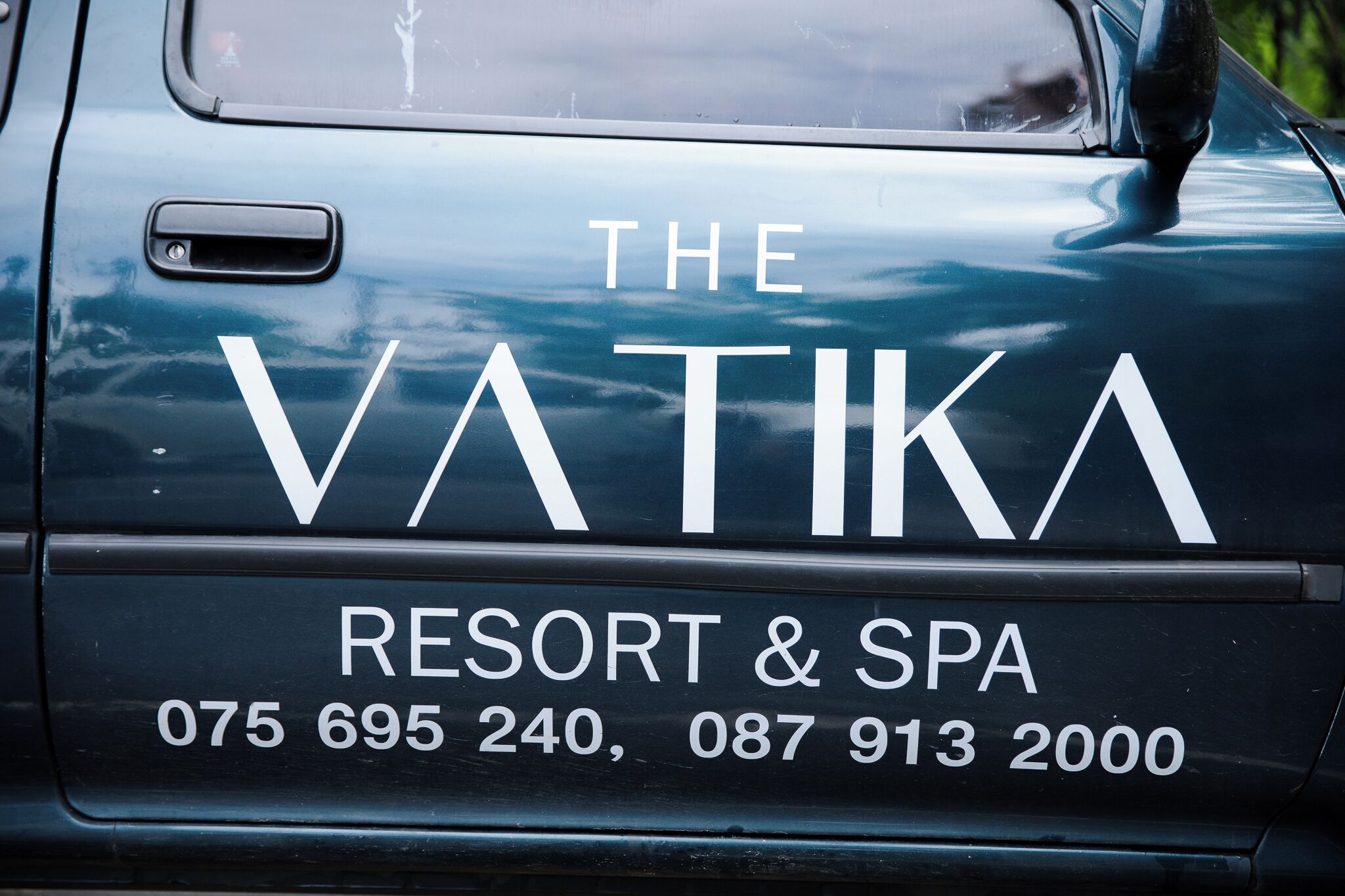 A vehicle with 'THE VATIKA RESORT & SPA' and contact numbers on the back.