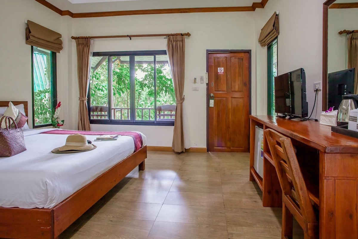 A hotel room with a bed, a desk, a television, and a door.