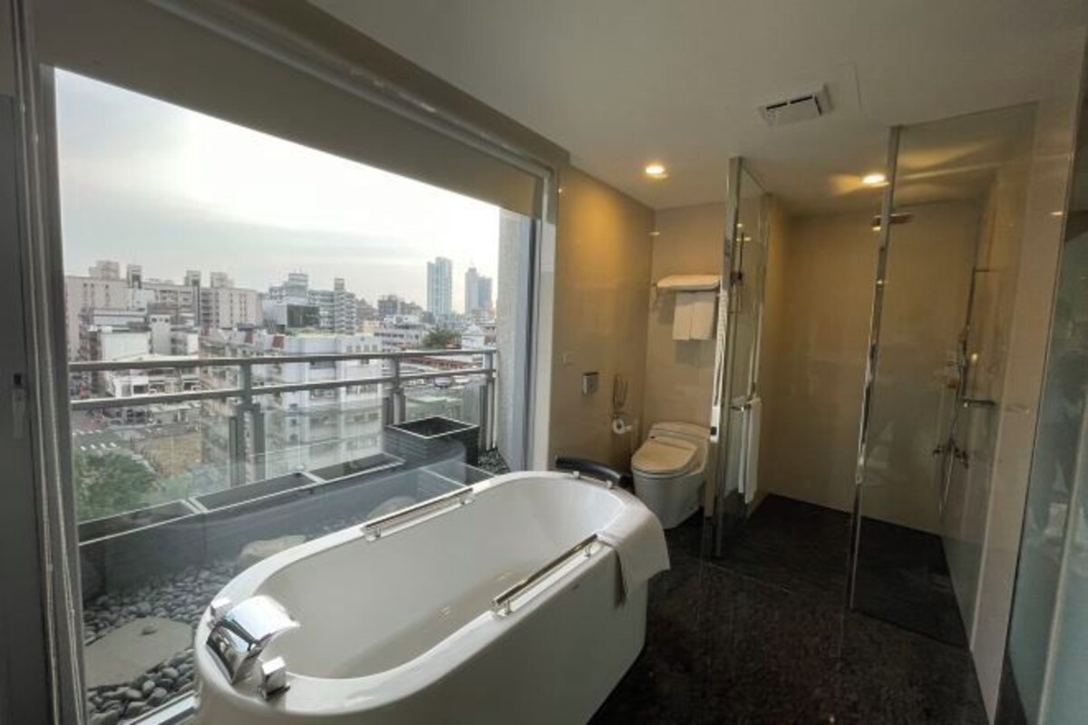 A modern bathroom with a bathtub, toilet, and shower.