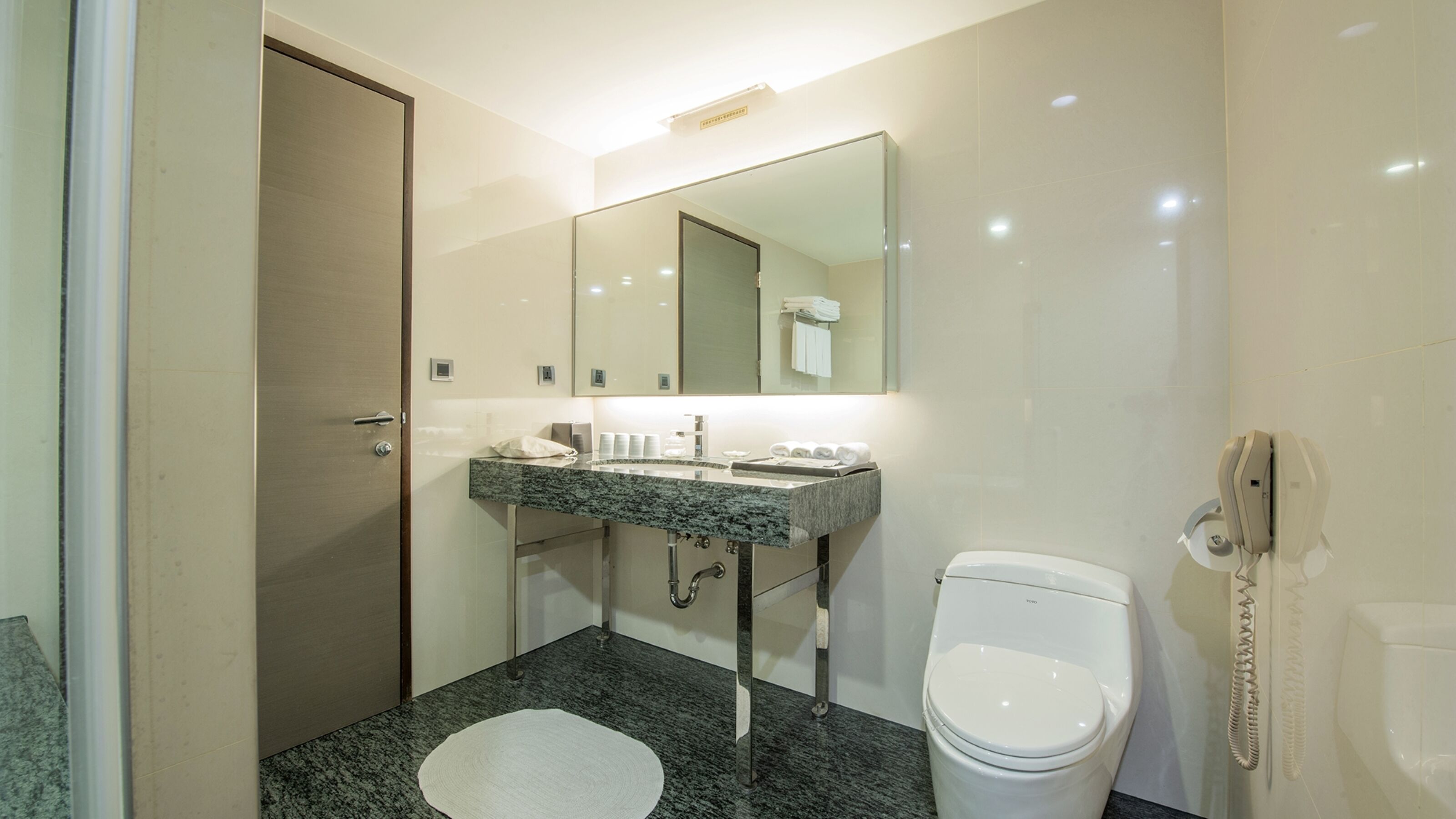 Un baño con lavamanos de mármol, inodoro y espejo.