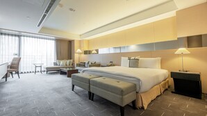 A modern hotel room with a large bed, a desk, a sofa, and a chair. - CHECK inn Select Taichung Dadun (Taichung)