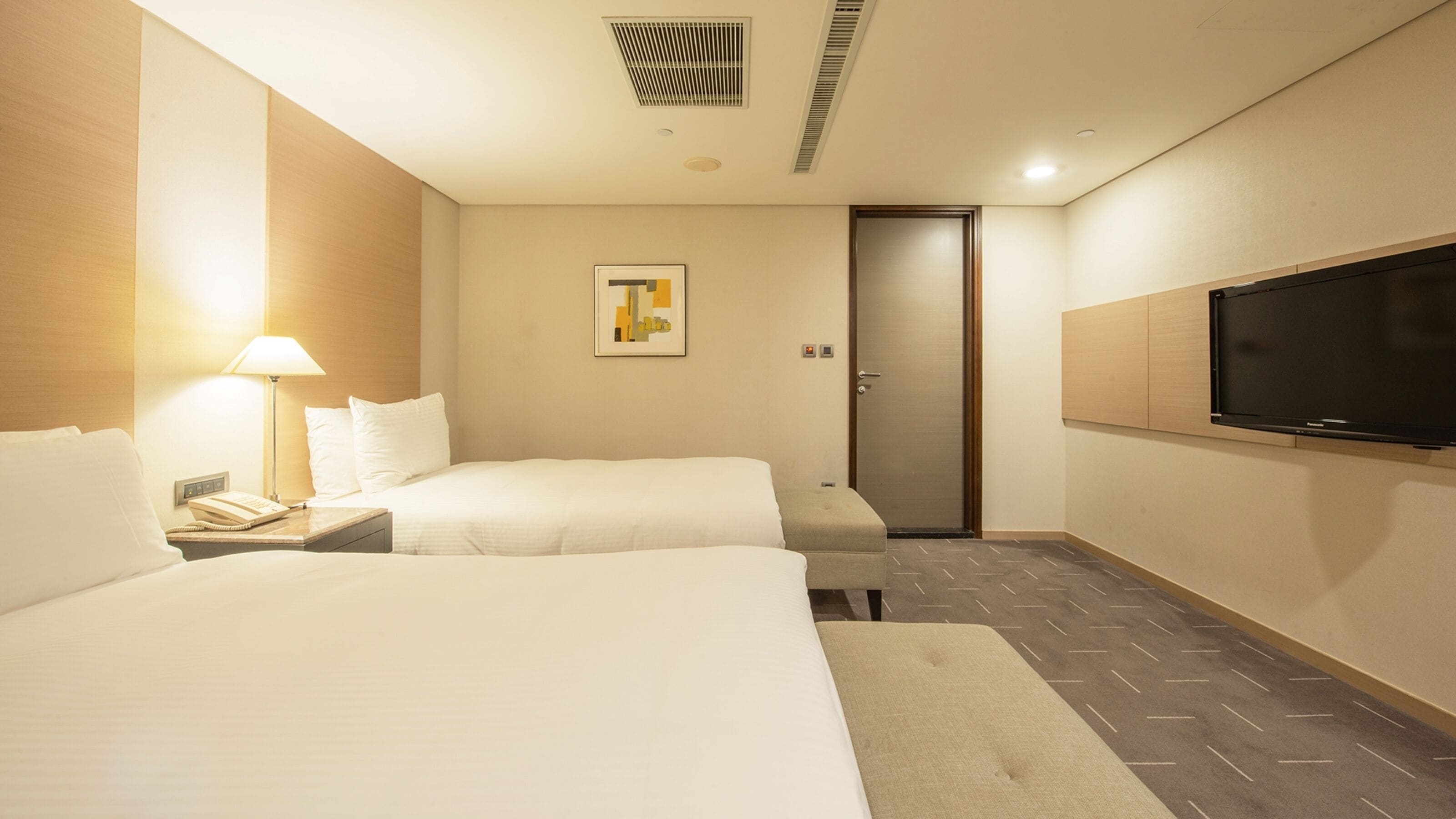 Une chambre d’hôtel avec deux lits, une télévision, une lampe et une porte.