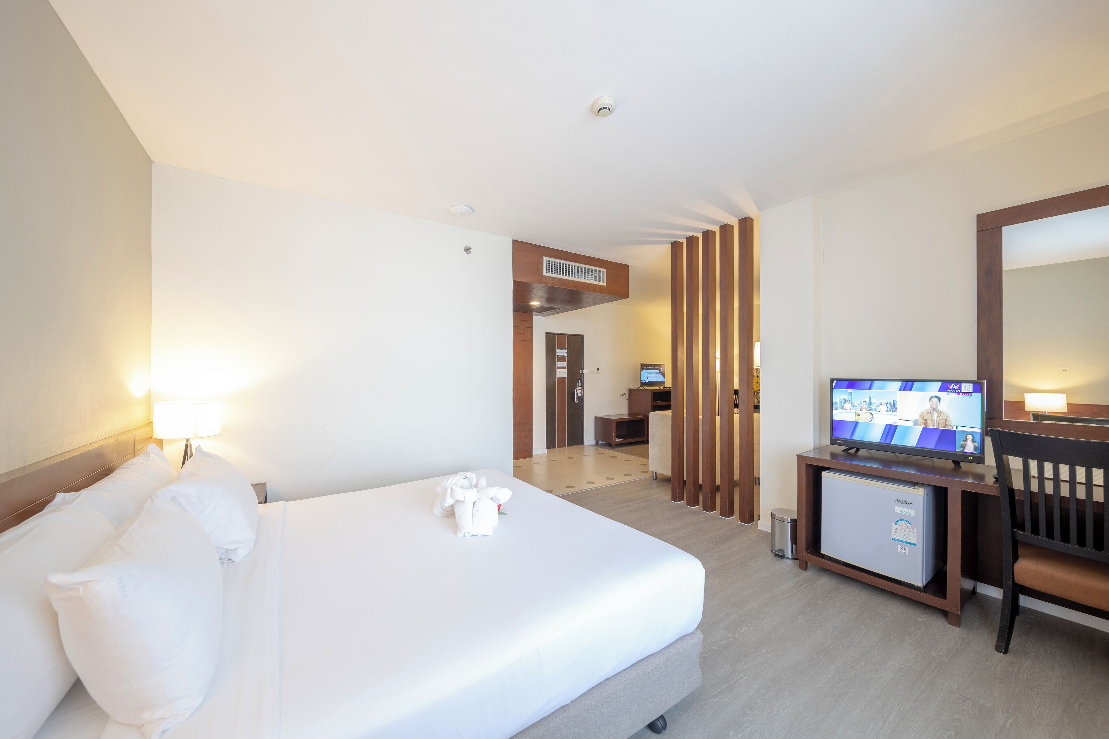 A hotel room with a bed, a TV, a desk, and a small fridge.
