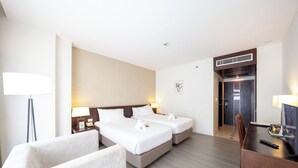A hotel room with two beds, a desk, a chair, a TV, and a lamp. - Golden Crown Grand Hotel (Hat Yai)