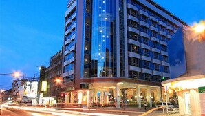 A multi-story hotel with a curved facade, large windows, and a ground-level entrance with a covered area. - Golden Crown Grand Hotel (Hat Yai)