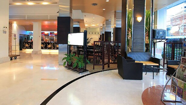 A spacious lobby with a curved seating area, a reception desk, and a large plant. - Golden Crown Grand Hotel (Hat Yai)