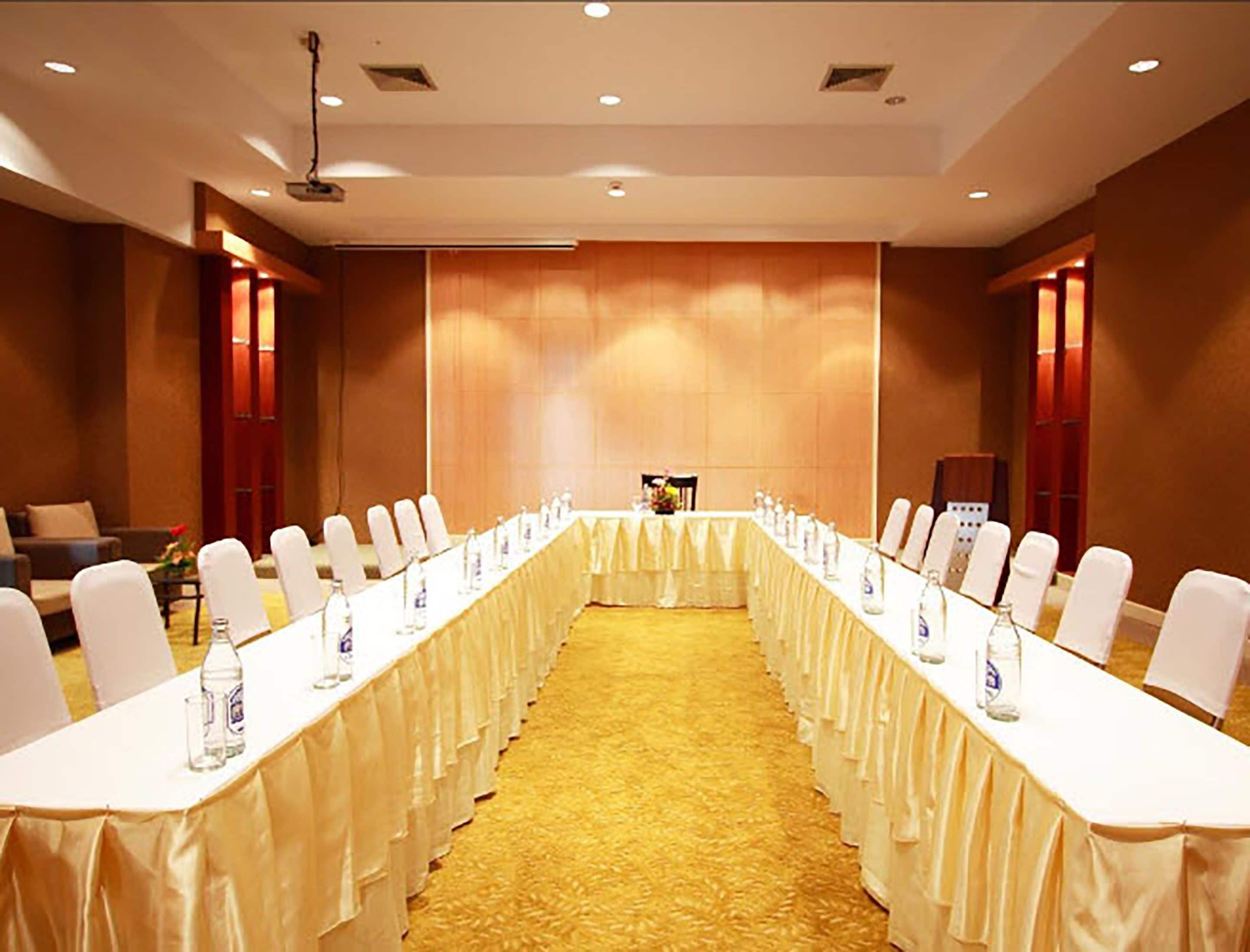 A conference room with a long table, white chairs, and a carpeted floor.