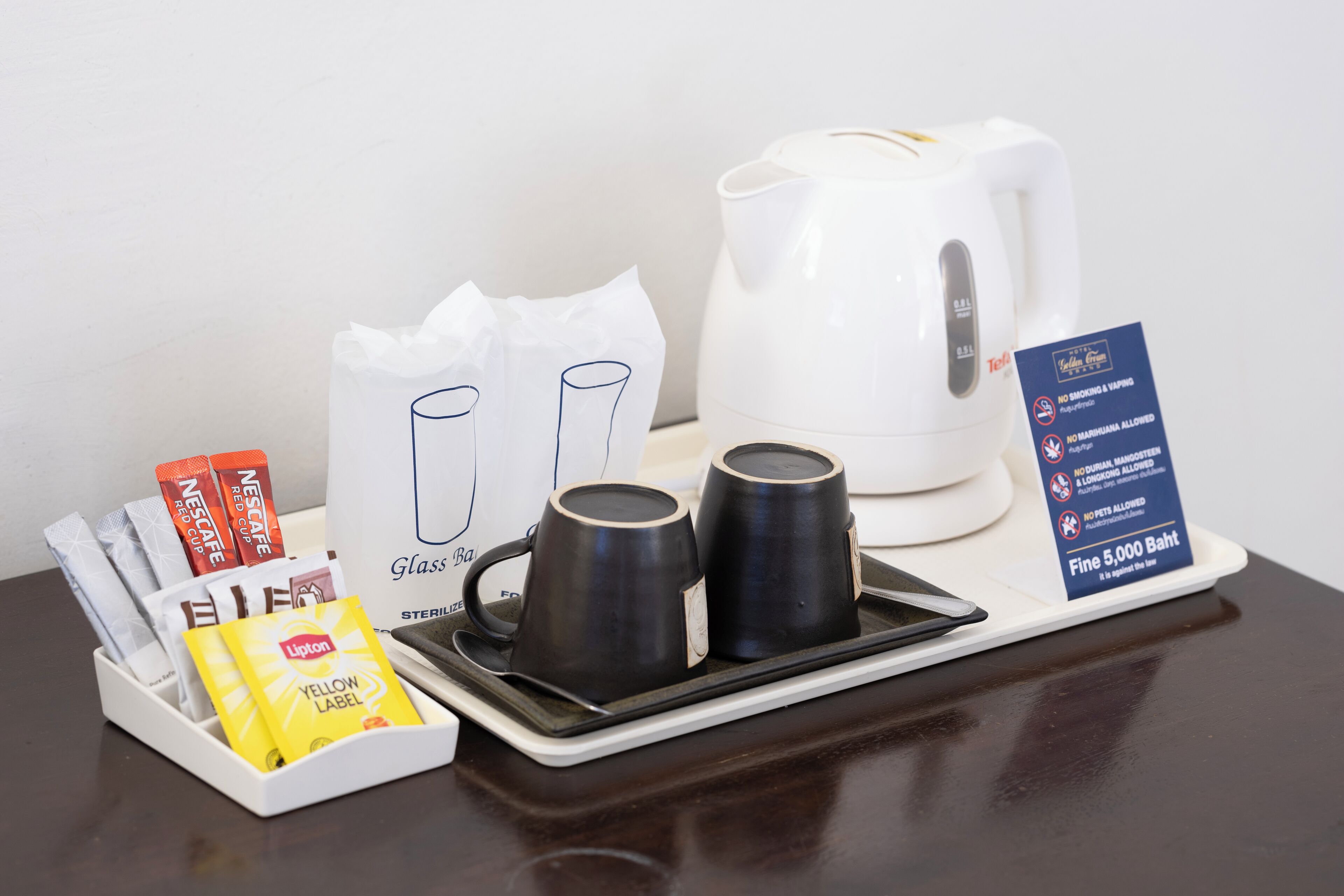 Een dienblad met een koffiezetapparaat, twee kopjes, een zakdoekendoos en een bordje waarop staat dat roken en huisdieren toegestaan zijn.