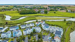 A residential area with modern houses, a small river, and surrounding fields. - Residence Pierre & Vacances Le Chant des Oiseaux (Courseulles-sur-Mer)