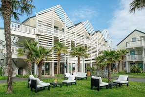 Un hotel con diseño arquitectónico moderno, zona de estar al aire libre y palmeras.